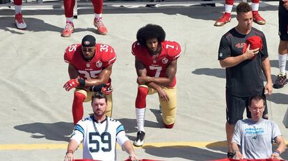 Colin Kaepernick y uno de sus compañeros se arrodillan ante el himno en señal de protesta.