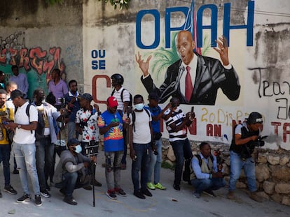 Um grupo de jornalistas se reúne em frente a um mural que mostra o presidente Jovenel Moïse perto da sua residência, onde ele foi assassinado a tiros na madrugada desta quarta-feira, 7 de julho.