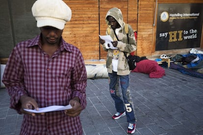 Alguns imigrantes leem as ofertas dos abrigos que os serviços sociais de Paris lhes ofereceram durante a evacuação do acampamento no qual estavam instalados na rua Pajol, na capital francesa.