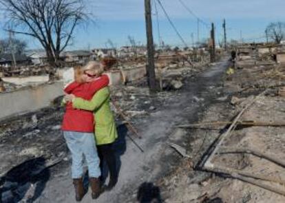 Dos vecinas se abraza en medio de los destrozos de muchas viviendas en el área de Breezy Point, Nueva York (EEUU), tras el paso de Sandy. EFE/Archivo