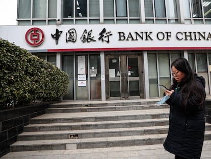 Una mujer camina junto a una sucursal bancaria en China.