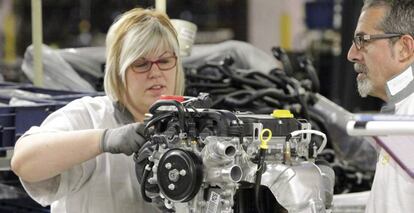 Una trabajadora de la cadena de montaje de la factoría que GM España tiene en Figueruelas (Zaragoza), coloca piezas en un motor.