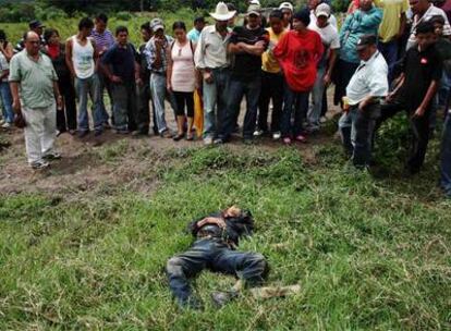 Varios vecinos contemplan el cadáver del joven que ha aparecido muerto en la localidad fronteriza con Nicaragua de El Paraíso. Según lo vecinos, el joven era partidario del retorno del presidente depuesto, Manuel Zelaya -quien ayer intentó entrar en Honduras por esa zona- por lo que fue arrestado por las fuerzas de seguridad.