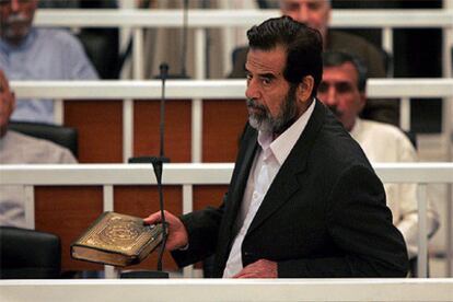 Sadam Husein muestra un ejemplar del Corán mientras se dirige al juez Razgar Mohamed Amín durante el juicio.