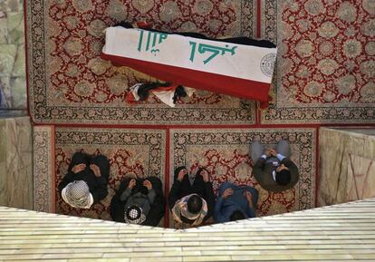 Cinco personas rezan junto al ataúd cubierto con la bandera de Irak durante su funeral en Nayaf, este jueves. Las protestas de Irak suponen un reto sin precedentes para la clase política chií que desde el derribo de Sadam en 2003 ha controlado las instituciones del Estado y las redes de afines subvencionados. Los iraquíes reclaman una reforma a fondo del sistema político.