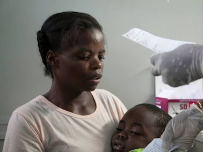 Una madre angole&ntilde;a sostiene a su hijo, que sufre de fiebre amarilla.
