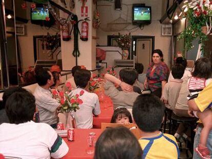 Varias personas ven un partido de f&uacute;tbol en un bar. 