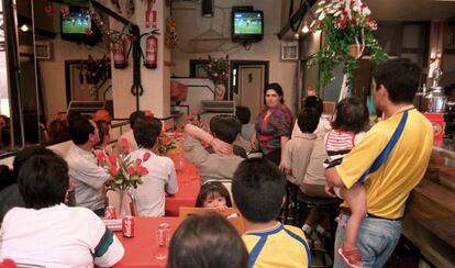 Varias personas ven un partido de f&uacute;tbol en un bar. 