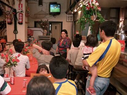 Varias personas ven un partido de fútbol en un bar.