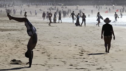 Donostiarras y visitantes disfrutan, esta tarde en la playa de la Zurriola de San Sebastián, del aumento de las temperaturas y los cielos despejados. 