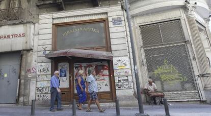 Peatones delante de un m&uacute;sico callejero en Atenas.