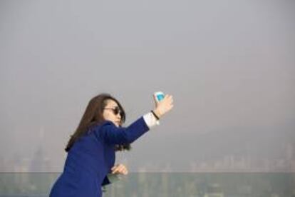 Una mujer toma una 'selfie' durante una visita a Victoria Peak mientras la bruma cubre el puerto de Victoria en Hong Kong, China. EFE/Archivo