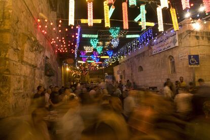 Palestinos caminan bajo las luces decorativas instaladas en los alrededores de la mezquita de Al Aqsa, en Jerusalén, después de romper el ayuno.