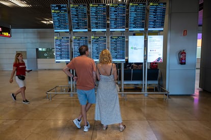 Dos personas revisan los paneles informativos del aeropuerto Adolfo Suárez Madrid Barajas.