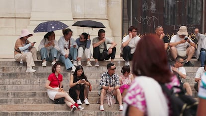 Tourists take shelter with umbrellas and hats on the steps of the Paris Opera, amid a heat wave.