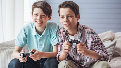 Dos niños adolescentes sonriendo y jugando a la consola.