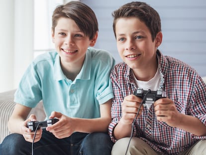 Dos niños adolescentes sonriendo y jugando a la consola.