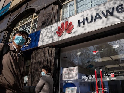 Nesta foto de arquivo, tirada em 22 de abril, pessoas passam diante de uma loja da Huawei em Pequim.