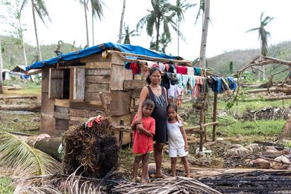 Una madre y sus hijos posan al lado de una palmera arrancada por el tifón Rai y que por escasos centímetros no les cayó encima. La familia ahora ha cubierto el techo de su casa con un plástico para evitar que la lluvia se cuele.