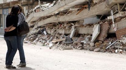 Dos mujeres se abrazan frente a un edificio derruido en Lorca, dos días después de los terremotos del 11 de mayo de 2011.