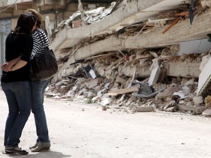 Dos mujeres se abrazan frente a un edificio derruido en Lorca, dos días después de los terremotos del 11 de mayo de 2011.