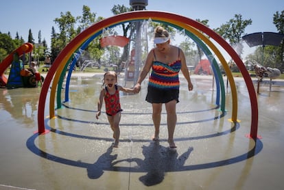 Una madre y su hija cruzan la fuente de un parque en Olds, Alberta, en Canadá, este 28 de junio. Los expertos han explicado que la subida de los termómetros en Canadá se debe a la alta presión estática, dando lugar a un fenómeno conocido como “domo de calor”.