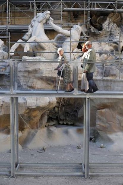 Três visitantes passeiam pela passarela sobre a Fontana de Trevi.
