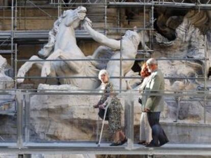 Três visitantes passeiam pela passarela sobre a Fontana de Trevi.