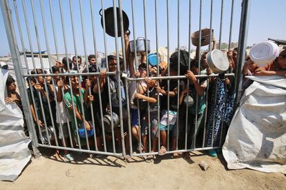 Desplazados palestinos en Deir al Balah, en el centro de Franja, esperan este martes tras unas verjas para recibir comida de organizaciones humanitarias.