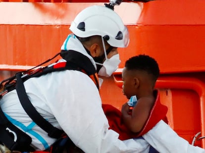 A migrant child is taken off a Spanish Coast Guard vessel in the port of Arguineguin, on the island of Gran Canaria.