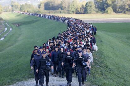 Migrantes son escoltados por la policía a las afueras de Brezice (Eslovenia).