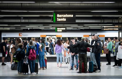 Pasajeros esperando el paso del tren, en los andenes de la estación de Sants, en Barcelona.