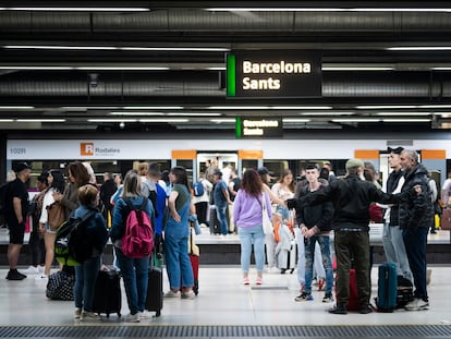 Pasajeros esperando el paso del tren, en los andenes de la estación de Sants, en Barcelona.