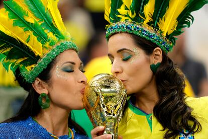 Dos aficionadas brasileñas besan una réplica de la copa del mundo en la víspera del Brasil - Serbia.
