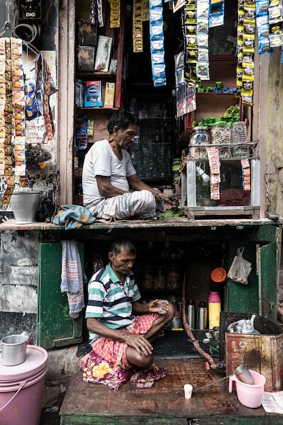 'Puesto de Té Callejero de Dos Pisos'. Una singular tienda de té de dos pisos prospera en un estrecho callejón de Calcuta, India, donde la tradición se fusiona con el ingenio. Abajo, el maestro del chai sirve té caliente en una taza, mientras que arriba, el vendedor de hojas de betel se ocupa de su artesanía. Una historia compleja de resiliencia y comunidad.