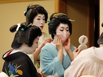 Senior geisha help Koiku put on a protective face mask to have a portrait photo taken of her wearing one for Reuters, before working at a party being hosted by customers, where she will entertain with other geisha, at Asada, a luxury Japanese restaurant, during the coronavirus disease (COVID-19) outbreak, in Tokyo, Japan, June 23, 2020. REUTERS/Kim Kyung-Hoon     SEARCH "GEISHA COVID-19" FOR THIS STORY. SEARCH "WIDER IMAGE" FOR ALL STORIES.