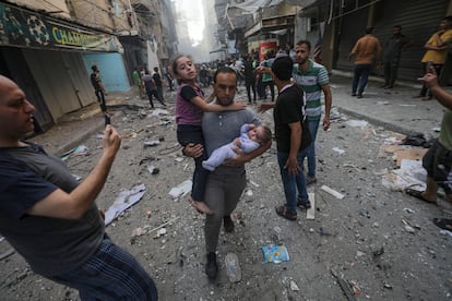 Un hombre corría el sábado con dos niños en brazos tras un ataque de Israel sobre Gaza.