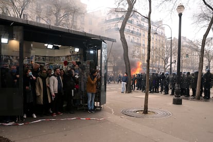Varios manifestantes se refugian bajo un quiosco en medio de los enfrentamientos con la policía en París, en el noveno día de huelga contra la reforma de pensiones del Gobierno francés.