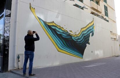 A man takes a picture of graffiti by Tunisian street artist The Inkman on a wall of Dubai's 2nd of December street, which is part of the government-funded Dubai Street Museum project, on February 6, 2017. 
The streets of Dubai may be known for architectural superlatives like Burj Khalifa, the highest of the world's high-rises, and the Middle East's largest shopping centre Dubai Mall. But a group of street artists now also wants to turn the concrete walls of a fast-growing urban sprawl into an open-air museum that celebrates Emirati heritage and speaks to everyone in the multicultural city.

 / AFP PHOTO / NEZAR BALOUT / RESTRICTED TO EDITORIAL USE - MANDATORY MENTION OF THE ARTIST UPON PUBLICATION - TO ILLUSTRATE THE EVENT AS SPECIFIED IN THE CAPTION