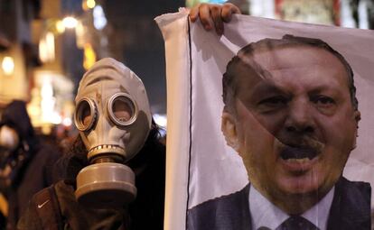 Un manifestante turco con una máscara sostiene un retrato del primer ministro Recep Tayyip Erdogan (d) durante la protesta antigubernamental.