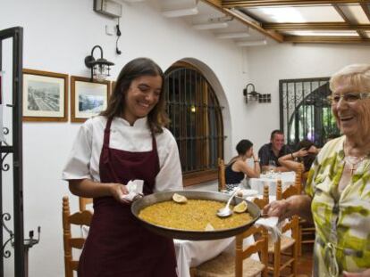 Rosa Devesa, a la derecha, sostiene un plato de arroz junto a su nieta Diana en su restaurante de D&eacute;nia.