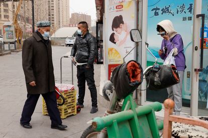 Residentes con mascarillas pasean por la ciudad de Aksu, en Xinjiang, región china donde vive la mayoría de la comunidad uigur.