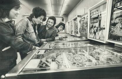 J&oacute;venes jugando con m&aacute;quinas de pinball