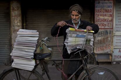 Un vendedor de periódicos carga su bicicleta en Nueva Delhi (India).