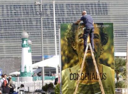 Un operario coloca en el Festival de San Sebastián un cartel de <i>Los condenados</i>, de Isaki Lacuesta, uno de los firmantes del manifiesto.