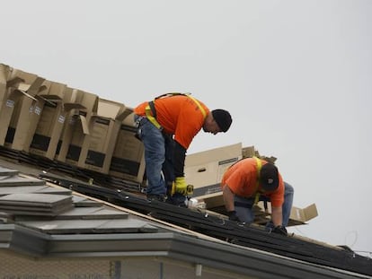 Trabajadores instalan paneles solares en una casa en construcción.