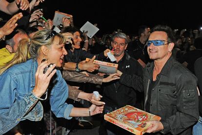 Bono, cantante de U2, distribuye pizzas a sus fans el jueves en Turín.