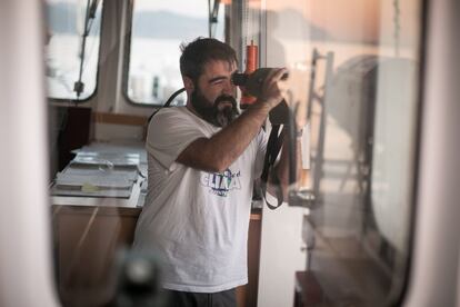 Un tripulante mira a tierra con un monocular desde el 'Rainbow Warrior'.