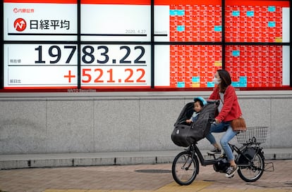 Una mujer y un niño frente a un indicador de la Bolsa de Japón, el lunes en Tokio.