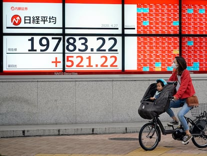 Una mujer y un niño frente a un indicador de la Bolsa de Japón, el lunes en Tokio.